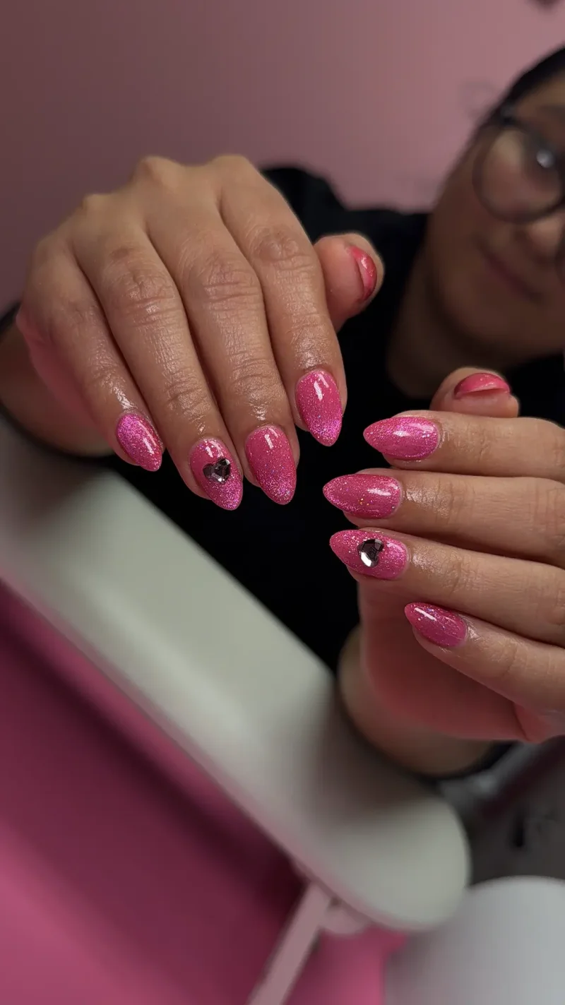 Hot pink glitter almond nails with rhinestone accents