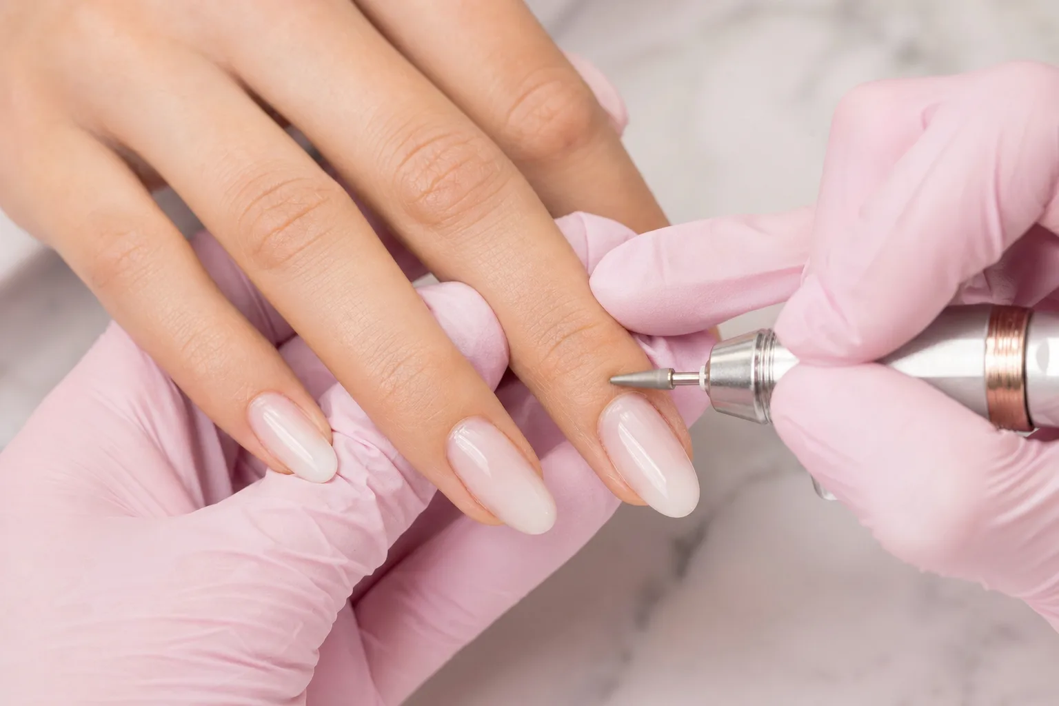 Nail technician working on a client's nails with an e-file