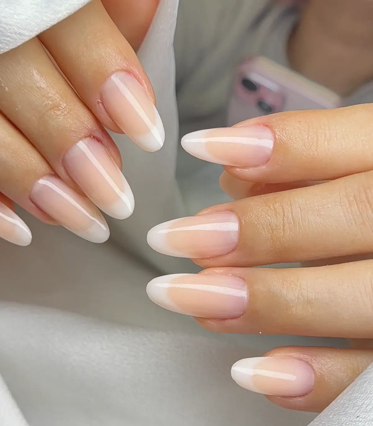 Almond French tip nails with nude base and crisp white V-tips at Polished by Kim