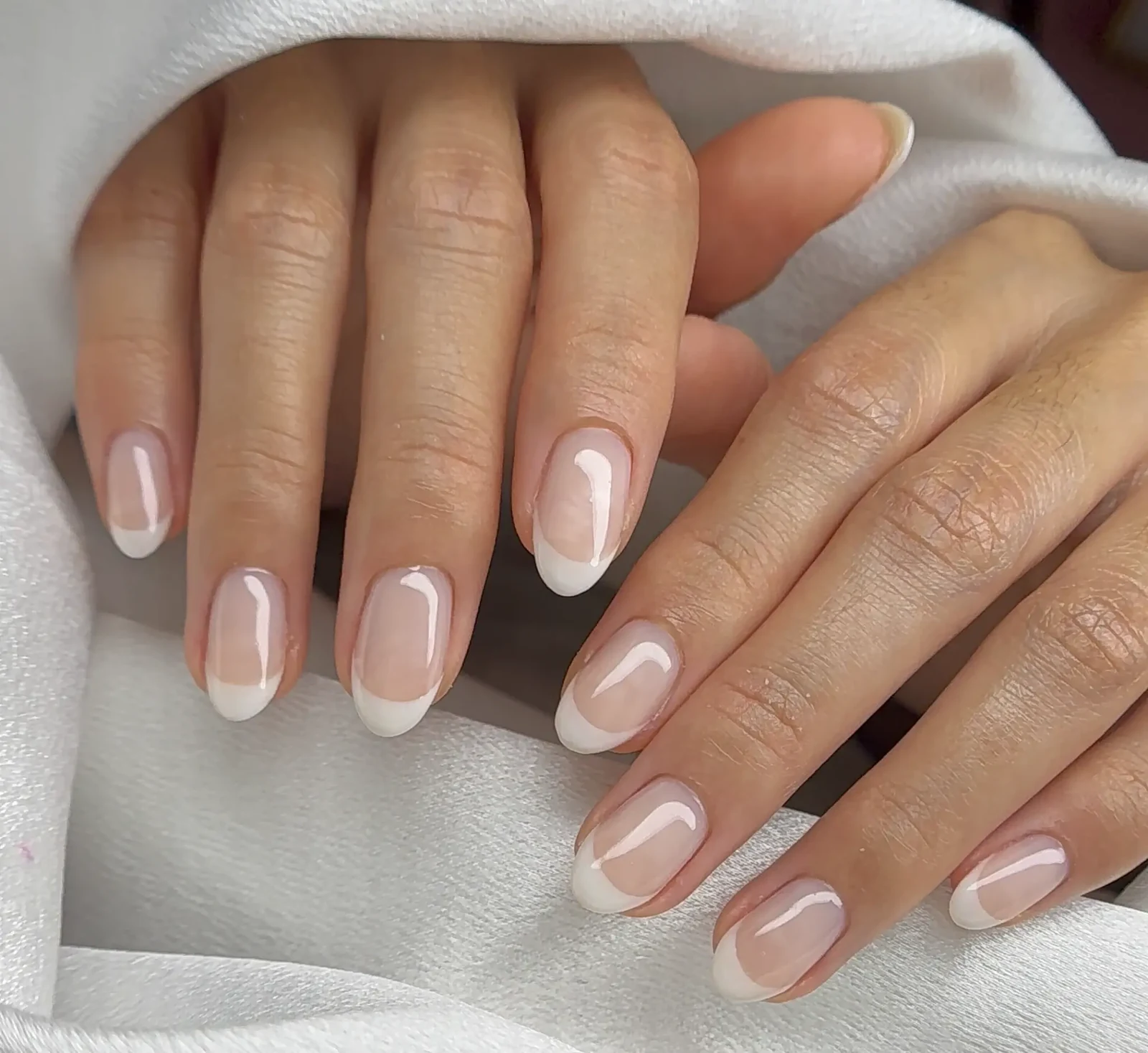 Classic white French manicure on almond nails with a sheer pink base by Polished by Kim