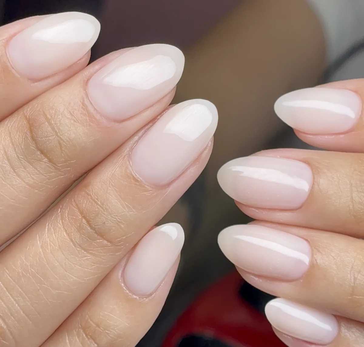 Milky white gel nails with a sheer pink finish on an almond oval shape by Polished by Kim