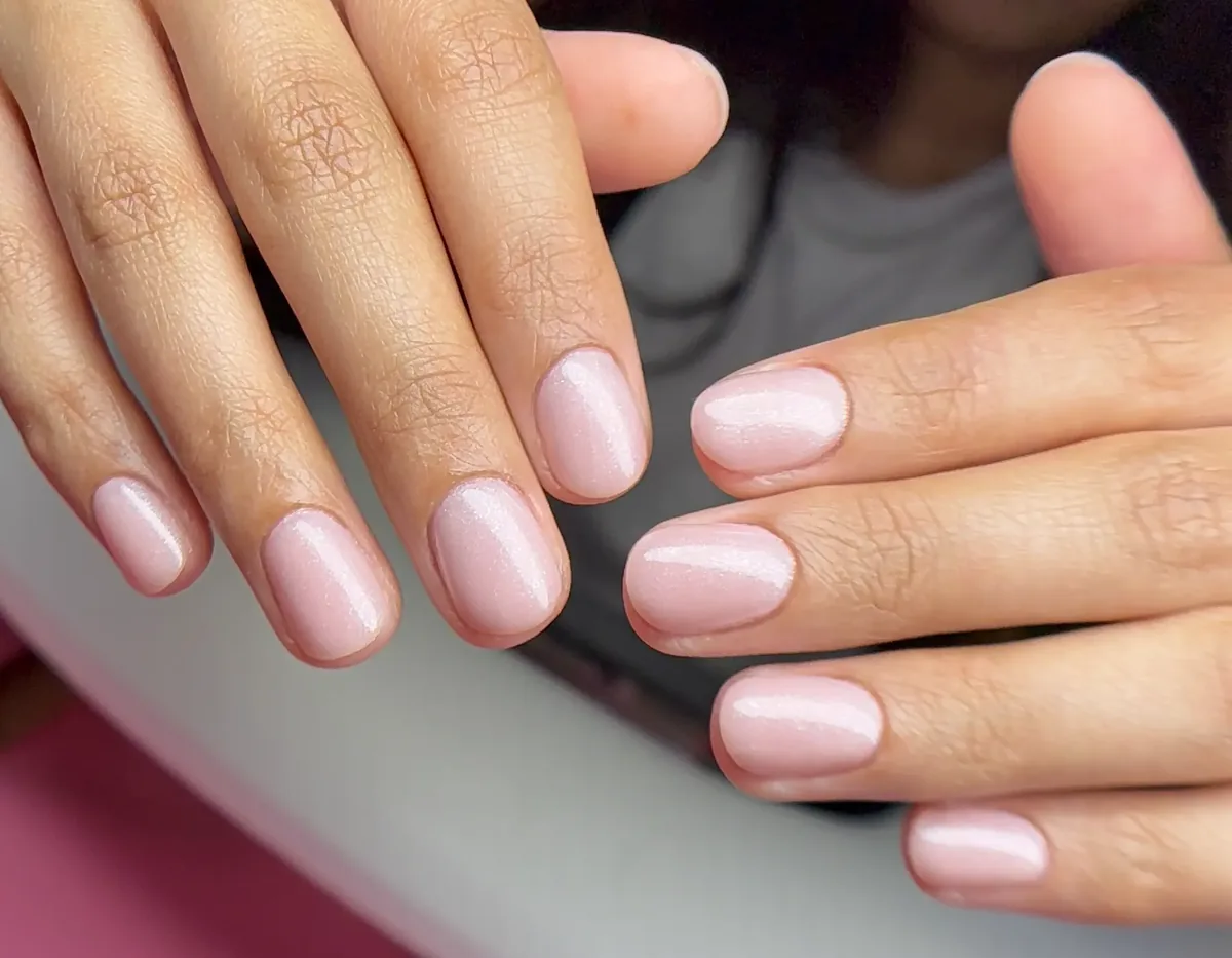 Both hands with a soft pearlescent pink gel manicure by Polished by Kim