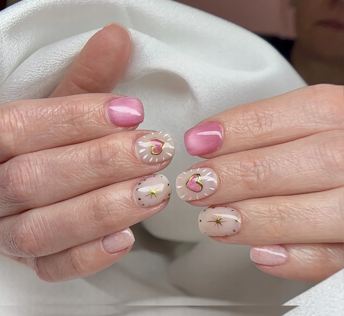 Short round nails with pink hearts and starburst nail art design by Polished by Kim