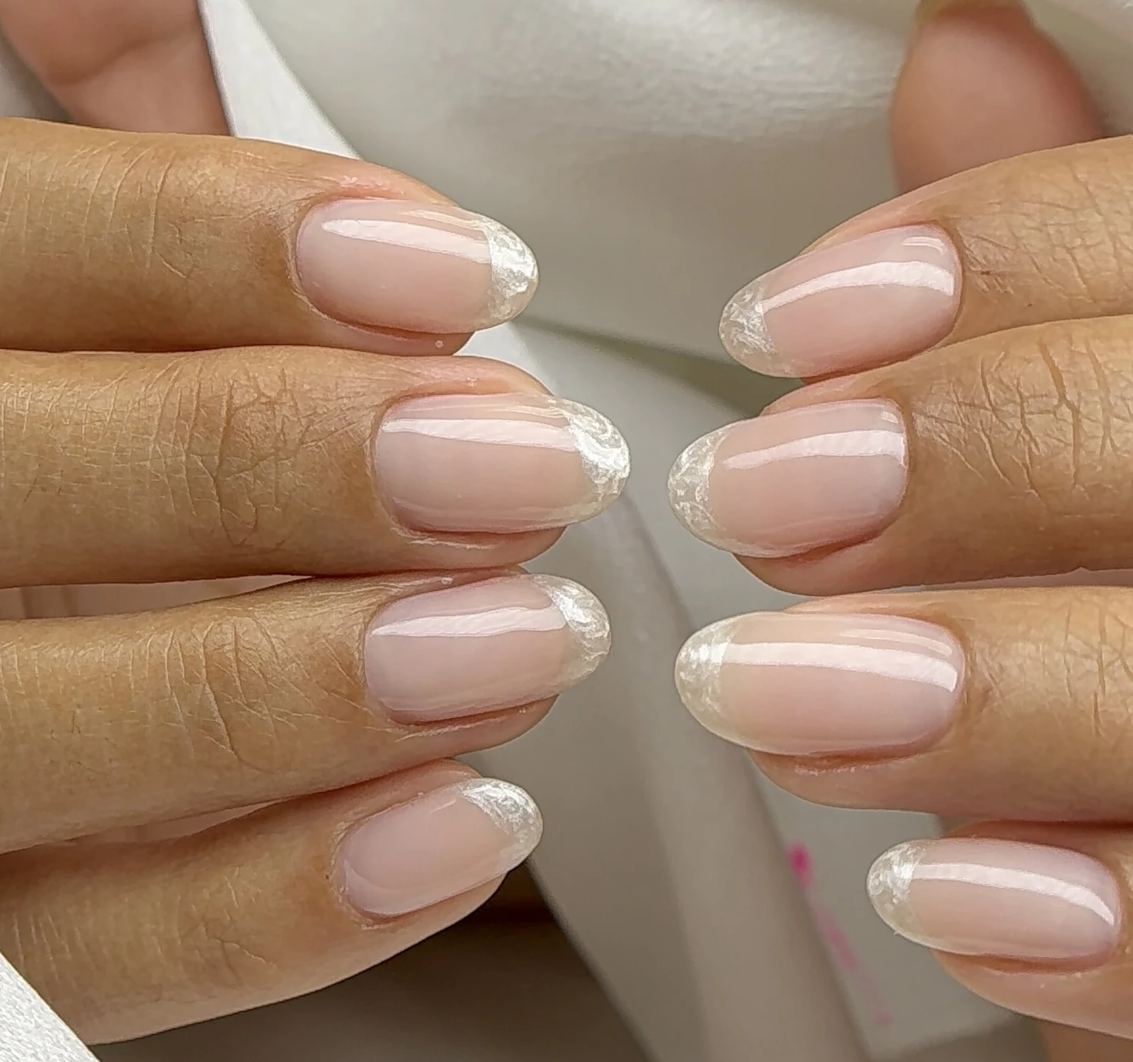 Sheer nude almond nails with iridescent glitter French tips by Polished by Kim